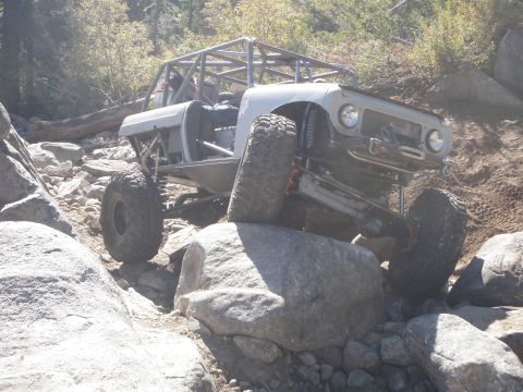 1961 International Scout 800 - This heavily modified off-road vehicle is tackling a challenging rocky terrain.