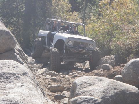 1961 International Scout 800 - This heavily modified off-road vehicle is tackling a challenging rocky path with large boulders.