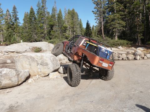 1961 International Scout 800 - This heavily modified off-road vehicle navigates a rocky trail with its tires angled on large boulders.