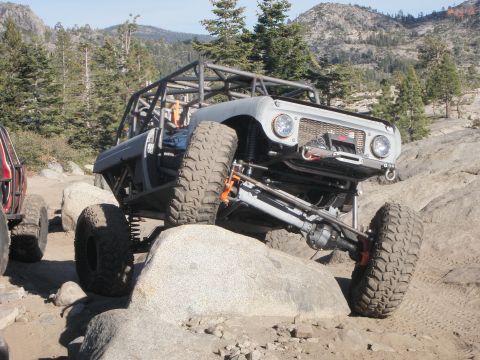 1961 International Scout 800 - This heavily modified vehicle navigates a rocky off-road course with another vehicle visible to the left.
