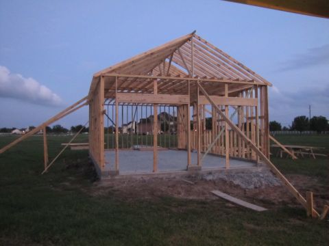 1995 Ford Bronco - A garage is shown in its early construction phase, with wooden beams forming the structure against a twilight sky.