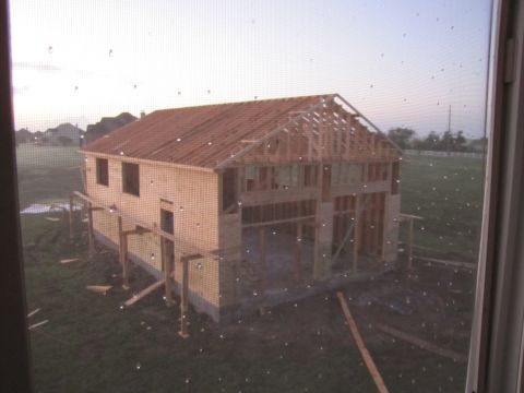 1995 Ford Bronco - A house is being built, with exposed wooden beams and framing visible against a hazy sky.