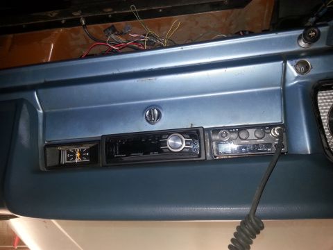 1982 Jeep Wagoneer - The dashboard features a clock, a modern stereo, and a CB radio, with exposed wiring above.