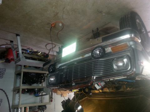 1982 Jeep Wagoneer - This truck is in a garage, possibly undergoing repairs or maintenance. The front grille and headlights are visible.