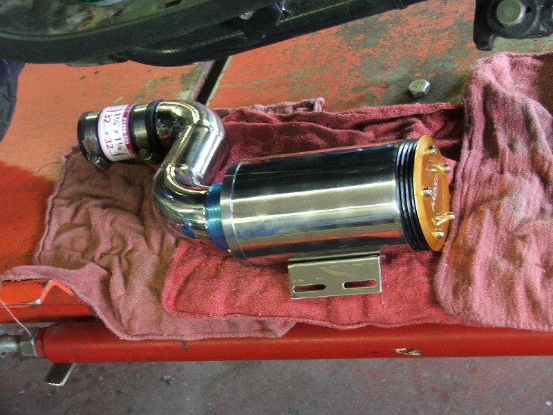 Chrome exhaust pipe with blue and orange accents on a red cloth