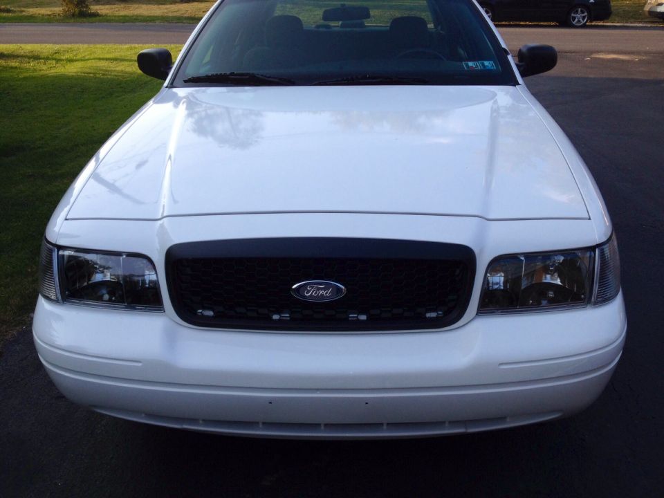 Front view of a white Ford Crown Victoria with a black grille and Ford emblem