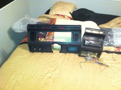 1982 Ford Bronco - Two dashboard sections and a car stereo with wiring are laid out on a bed.