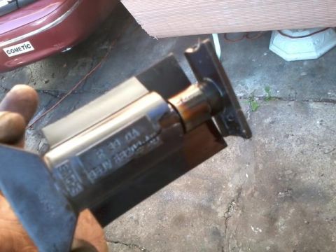 1998 Ford Crown Victoria - A mechanical part is held in front of a red car's rear quarter panel.