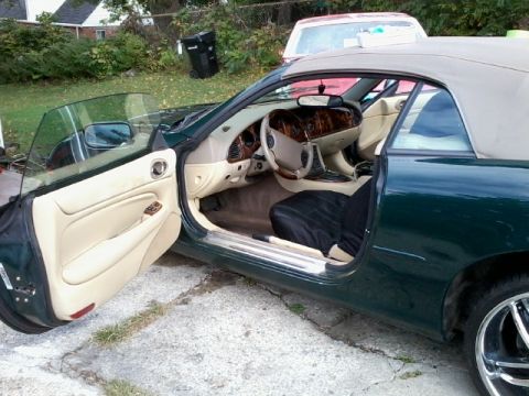 1998 Ford Crown Victoria - Interior view of a green convertible with tan upholstery and wood trim. Another vehicle is parked behind it.