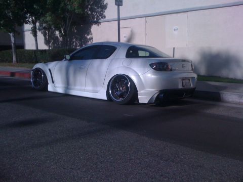 1968 Ford Mustang - Modified white Mazda RX-8 seen from the rear quarter angle on a street.