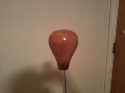 1998 Ford Crown Victoria - A wooden gear shift knob is shown against a textured wall, with a door frame visible on the right.