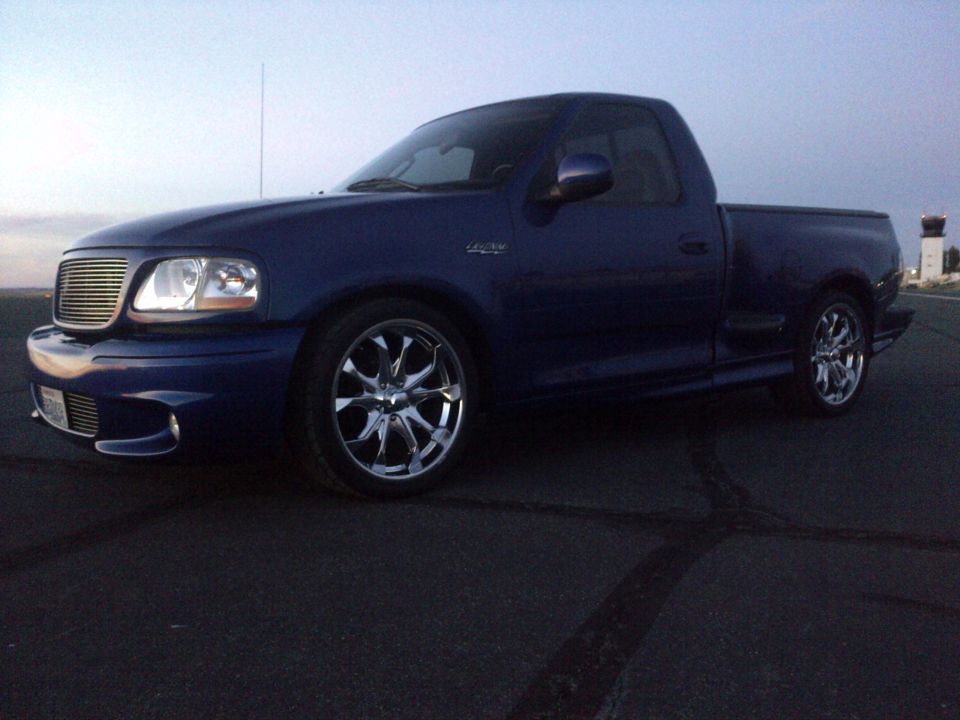 Blue pickup truck with chrome wheels parked on asphalt