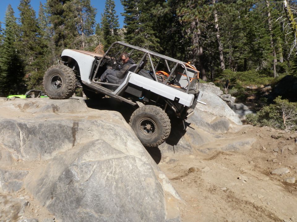 Custom off-road buggy with roll cage navigating rocky terrain