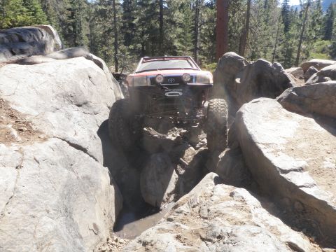 1961 International Scout 800 - An off-road vehicle navigates a challenging rocky terrain, its front end visible as it maneuvers through boulders.