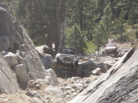 1961 International Scout 800 - A 1961 International Scout 800 tackles a challenging rocky off-road path, with another vehicle following behind.