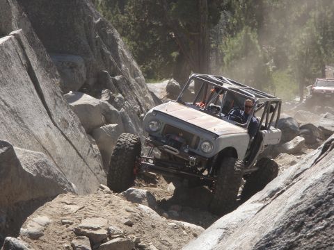 1961 International Scout 800 - This modified vehicle is tackling a challenging rocky off-road course, with another vehicle following behind.