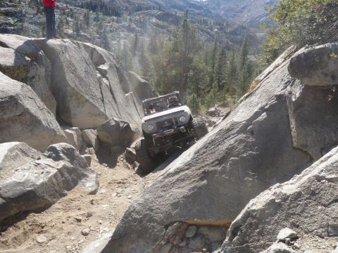 1961 International Scout 800 - An off-road vehicle navigates a challenging rocky path in a mountainous landscape.