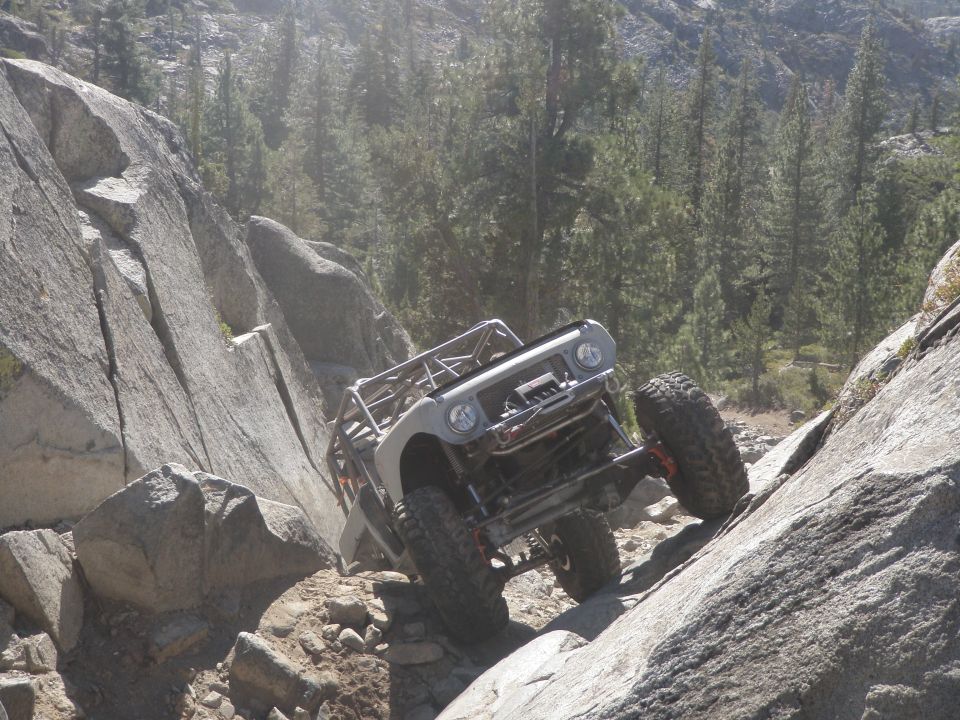 1961 International Scout 800 on a rocky incline, silver body with roll cage, large off-road tires