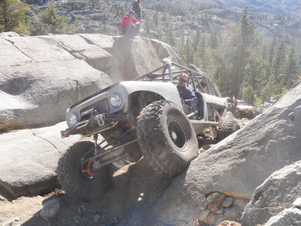 Custom buggy crawling over large rocks with people watching