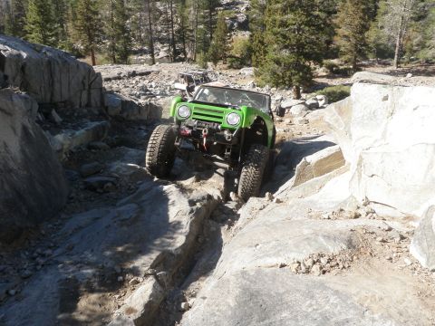 1961 International Scout 800 - A modified 1961 International Scout 800 navigates a challenging rocky terrain, with another off-road vehicle visible in the background.