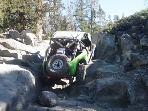 1961 International Scout 800 - This off-road buggy is shown navigating a challenging rocky trail, with its spare tire mounted on the back.