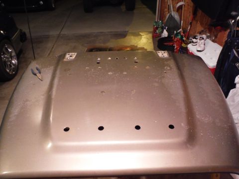 2005 Jeep Wrangler - A gold hood from a 2005 Jeep Wrangler is shown, with holes visible for mounting hardware.