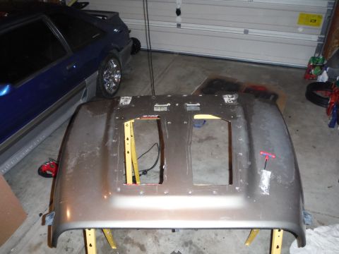 2005 Jeep Wrangler - A car hood is disassembled and placed on sawhorses, with another vehicle visible in the background.