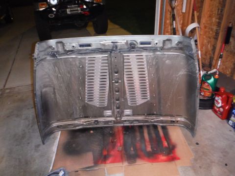 2005 Jeep Wrangler - Underside of a Jeep Wrangler hood, with a black Jeep visible in the background.