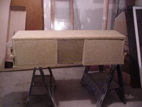 1993 Ford Bronco - Custom carpeted rectangular enclosure with two sub openings resting on metal sawhorses in a garage workspace.