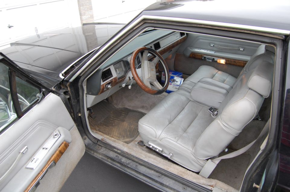 1985 Mercury Grand Marquis interior with gray leather seats, wood trim, and a tan dashboard
