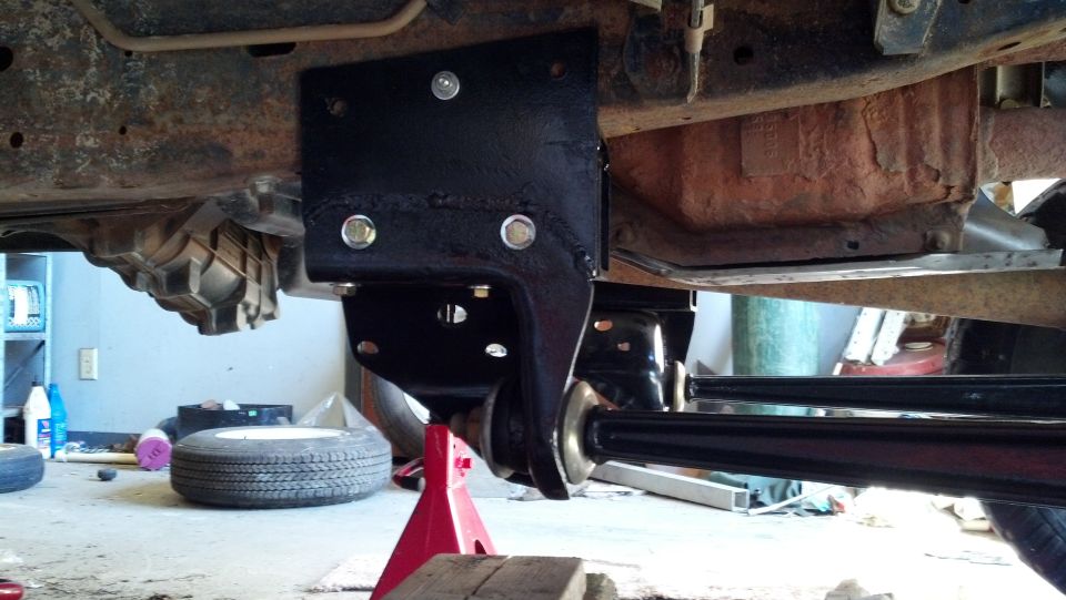 Truck chassis with black suspension bracket, red jack stand, and spare tire on the floor