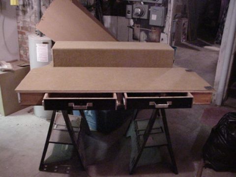 1993 Ford Bronco - Front view of an unfinished particle-board cargo console on sawhorses in a basement, with two open drawer boxes riding on metal slides bene…