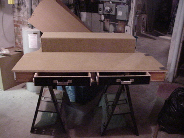 Unfinished particle board cargo console with two open drawers on sawhorses