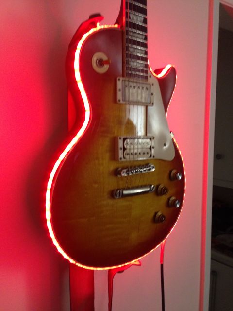 1989 Mazda MX-6 - An electric guitar with a sunburst finish is illuminated by red neon lights.