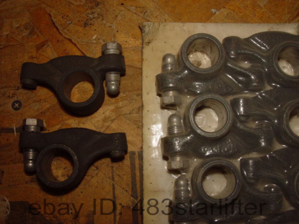 Two engine rocker arms in foreground, set of eight in plastic packaging in background