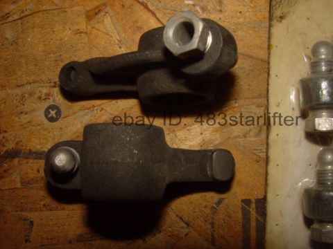 1969 Ford Fairlane - Close-up view of two dark metal engine rocker arms, one with a nut, on a wooden background.