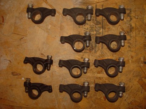 1969 Ford Fairlane - Set of twelve engine rocker arms, likely for a classic car or truck, displayed on a wooden background.