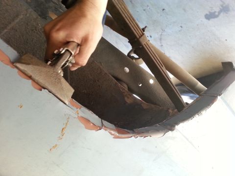 1982 Jeep Wagoneer - Scraping away rust from the underbody of a vehicle, revealing the leaf spring and frame components.