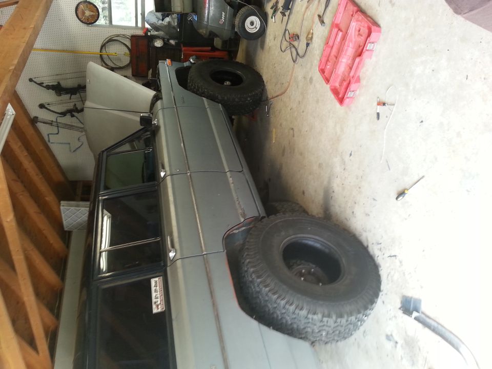 1982 Jeep Wagoneer parked in a garage with hood up, spare tire visible