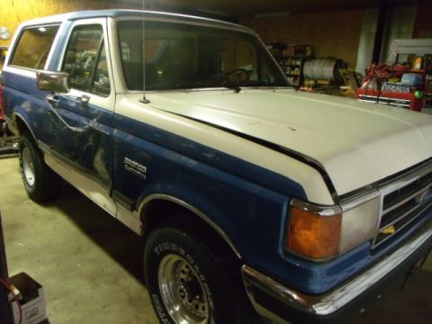 1984 Ford Bronco - This two-tone blue and white Ford Bronco is parked inside a garage or workshop.