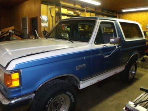1984 Ford Bronco - This Ford Bronco, likely from the late 1980s, is parked indoors with its hood open.