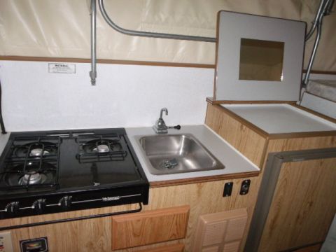 1984 Ford Bronco - The interior of a camper shows a kitchen area with a stove and sink.