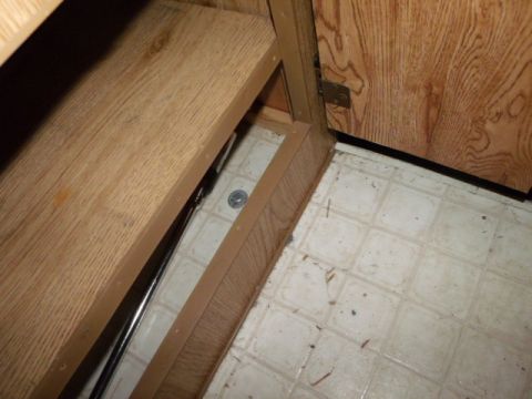1984 Ford Bronco - Close-up view of the interior of a cabinet, showing wooden panels and a section of the floor.