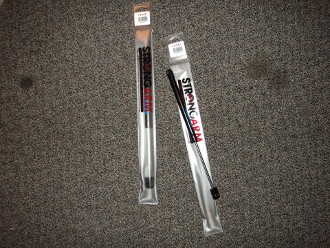 2004 Mercury Grand Marquis - Two new Strongarm lift supports are shown packaged on a carpeted floor.