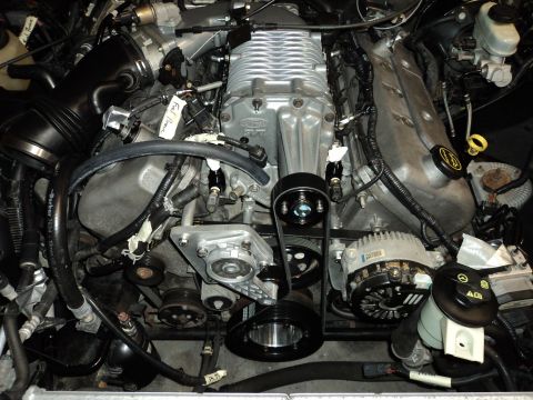 2004 Mercury Grand Marquis - Engine bay a silver supercharger and associated belt-driven components.