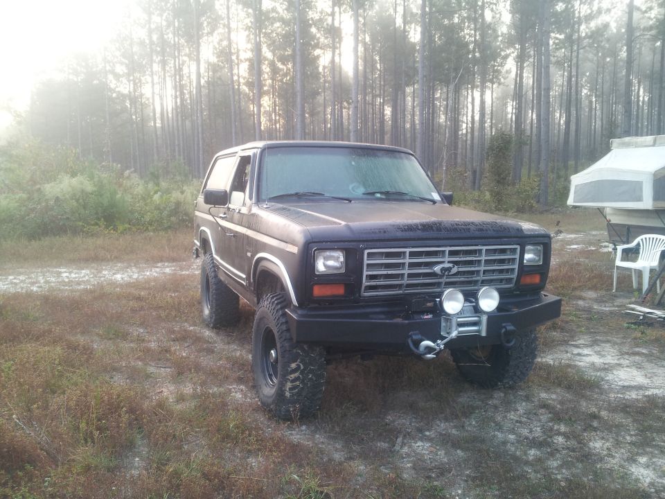 1980s Ford Bronco with a winch and auxiliary lights on the front bumper.
