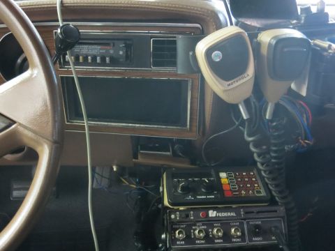 1991 Ford LTD Crown Victoria - vehicle center stack fitted with a factory radio, a Motorola handheld mic and a Federal Signal siren control box mounted below the dash.