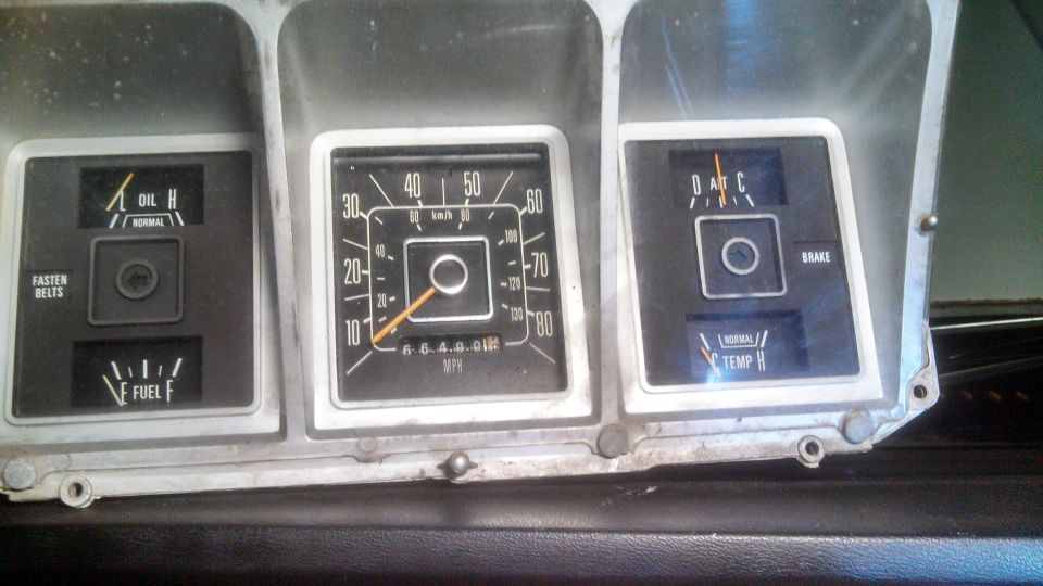 Vintage vehicle dashboard gauges including speedometer, oil, fuel, temperature, and brake warning lights.