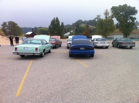 2003 Ford Crown Victoria - A light green two-door sedan with its hood open is parked in a gravel lot next to several other cars. The car has a black vinyl roof and ap…