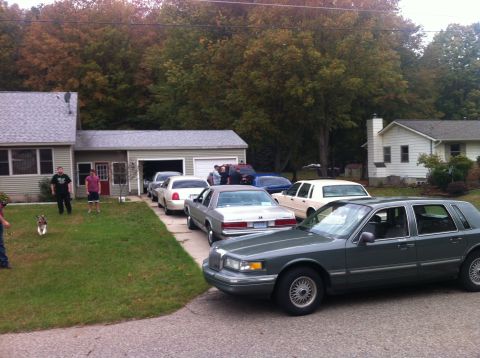 2003 Ford Crown Victoria - A dark sedan is parked in a residential driveway, with several other vehicles also present.